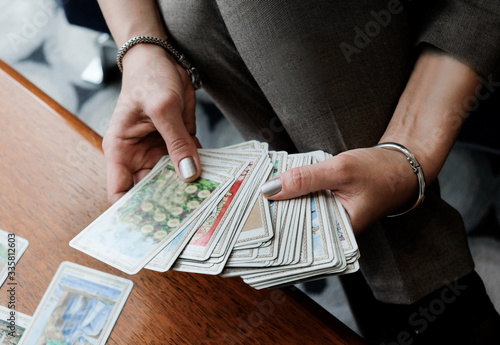 Woman’s hand keep Tarot cards on wooden the table. Divination, occult, esoteric concept.