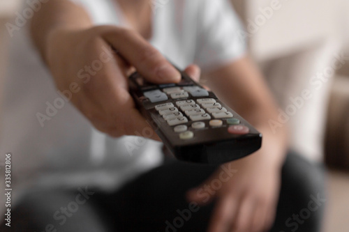 Young male student watching tv using the remote