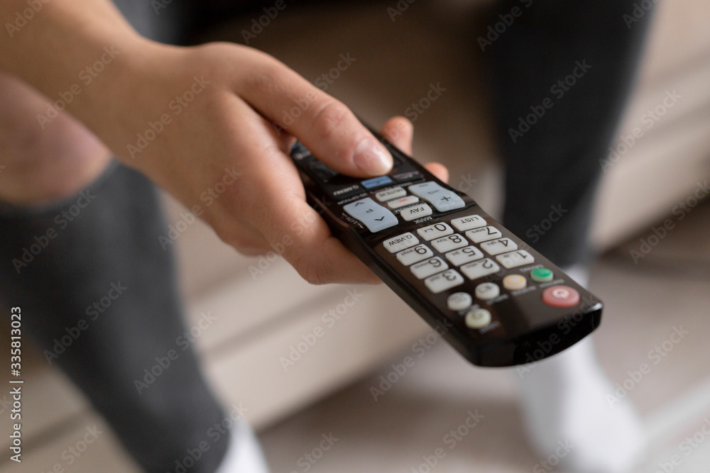 Young male student watching tv using the remote