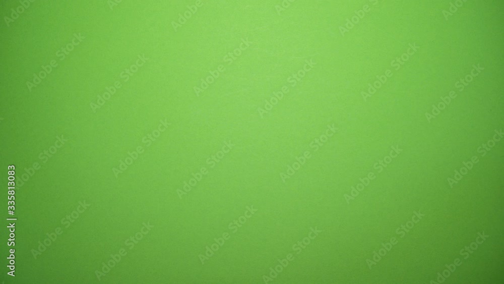 Hands tearing white paper vertical revealing a green screen Hands tearing white paper vertical revealing a green screen