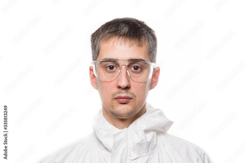 Portrait of young man in protective white medical uniform during coronavirus pandemic. Epidemic, pandemic of coronavirus covid 19. Portrait of young man in protective white medical uniform during coronavirus pandemic. Epidemic, pandemic of coronavirus covid 19.