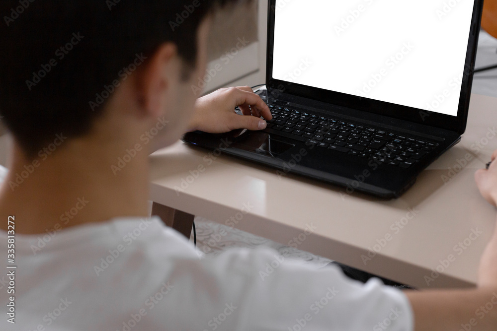 Teenage student studying at home using his tablet and computer Teenage student studying at home using his tablet and computer