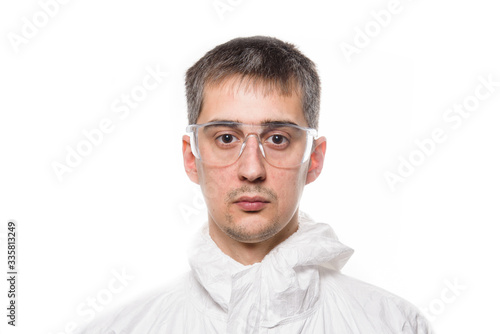 Fototapeta Naklejka Na Ścianę i Meble -  Portrait of young man in protective white medical uniform during coronavirus pandemic. Epidemic, pandemic of coronavirus covid 19.