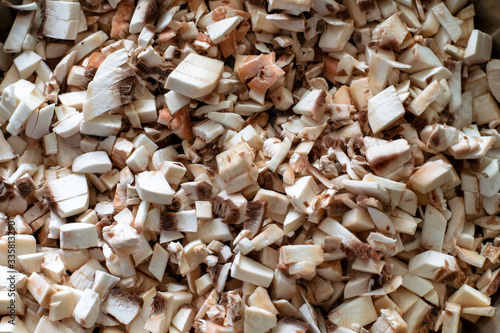 Raw mushrooms are cut into small pieces. Raw chopped champignons