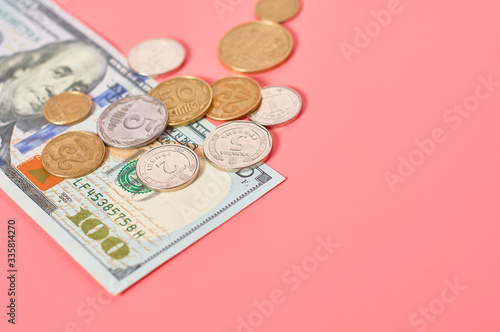 Banknotes of usa and ukrainian coins on pink background. Payment of pensions, salaries. Bank loan. Business concept