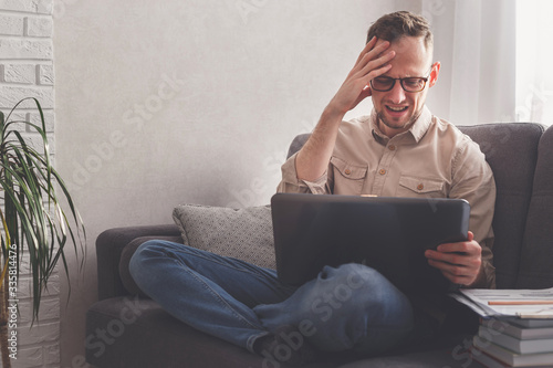 Alarmed man at the computer at home. Reads news, works.