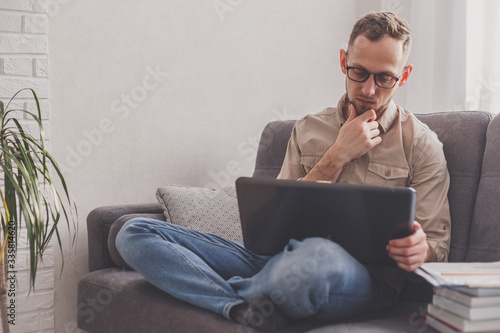 Remote Job. Man working on laptop sitting on sofa at home. photo