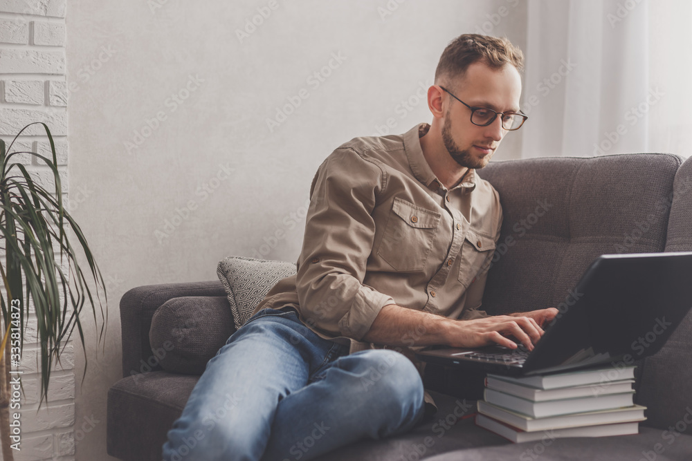 Remote Job. Man working on laptop sitting on sofa at home. Remote Job. Man working on laptop sitting on sofa at home.