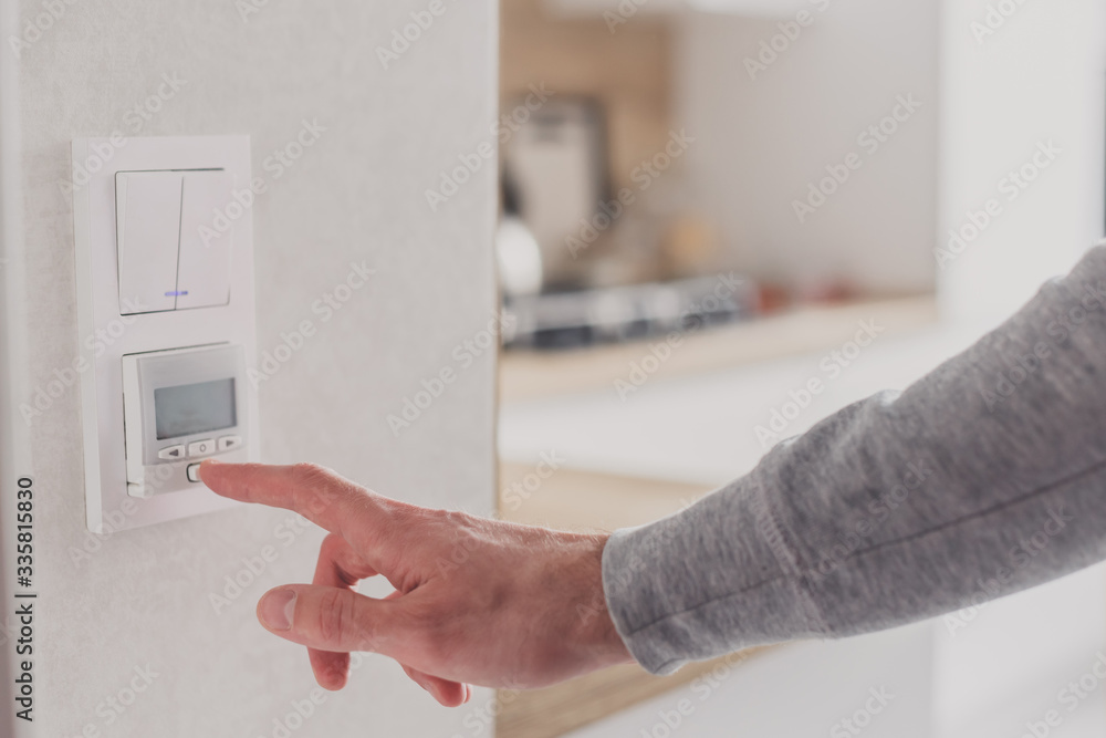 Men hand setting the temperature on control panel of DHW or central heating. Men hand setting the temperature on control panel of DHW or central heating.