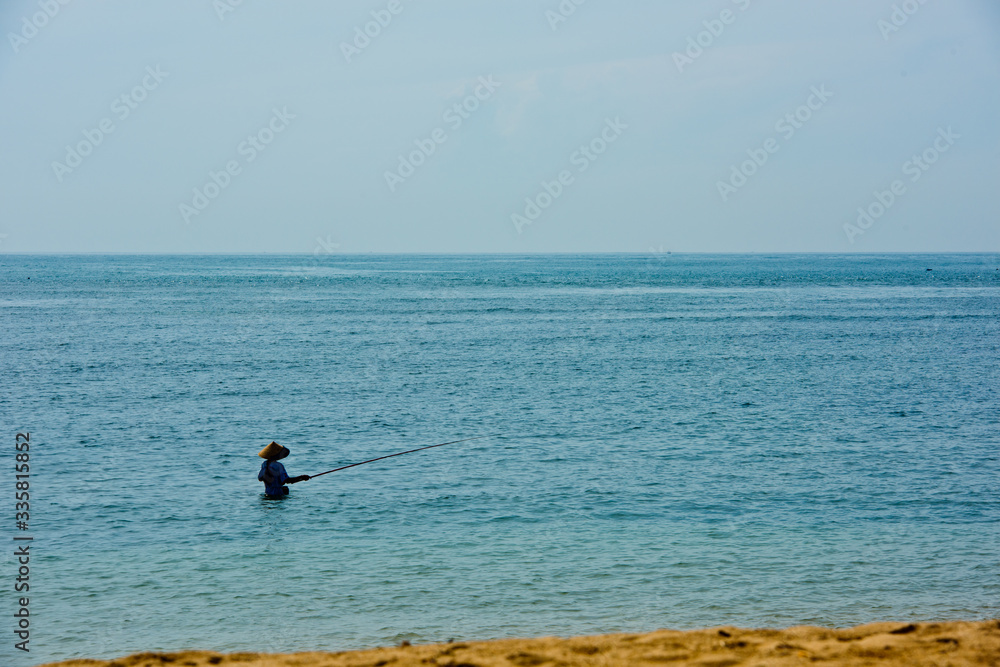 Traditional fisherman fishing rod catches the fish in the bay. Bali, Indonesia.