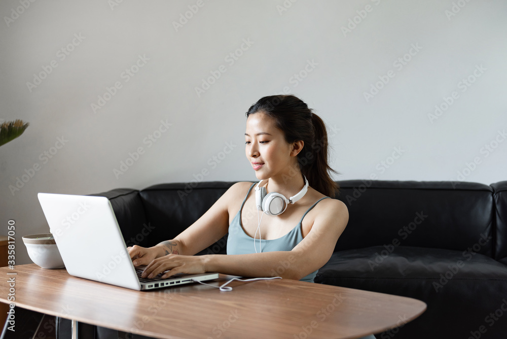 A young Asian woman using a computer in the living room A young Asian woman using a computer in the living room