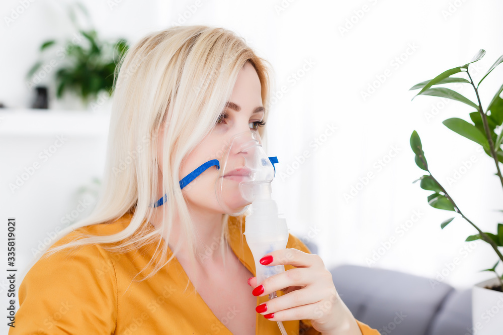 Young woman using nebulizer for asthma and respiratory diseases at home Young woman using nebulizer for asthma and respiratory diseases at home