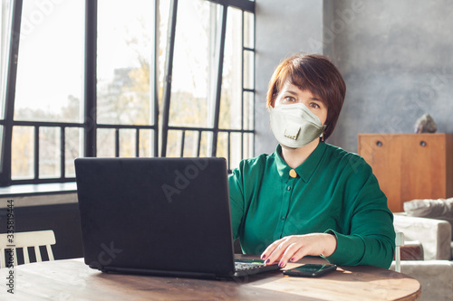 Mid adult business woman in face mask working laptop computer indoors