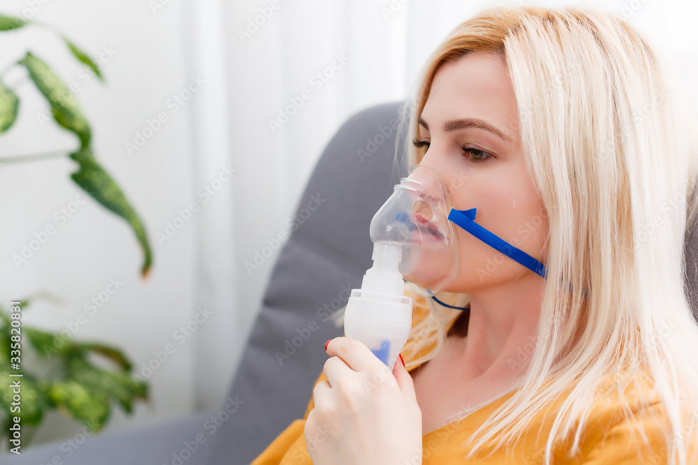 woman makes inhalation nebulizer at home. holding a mask nebulizer inhaling fumes spray the medication into your lungs sick patient. self-treatment of the respiratory tract using inhalation nebulizer woman makes inhalation nebulizer at home. holding a mask nebulizer inhaling fumes spray the medication into your lungs sick patient. self-treatment of the respiratory tract using inhalation nebulizer