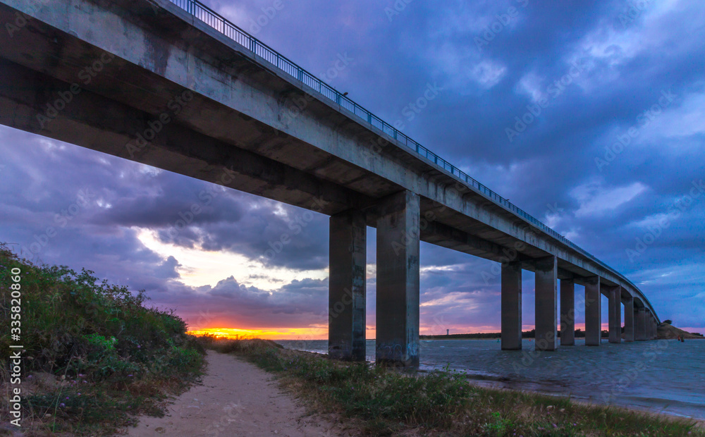 Low sunset under the bridge to Noirmoutier, France, with dramatic purple clouds Low sunset under the bridge to Noirmoutier, France, with dramatic purple clouds
