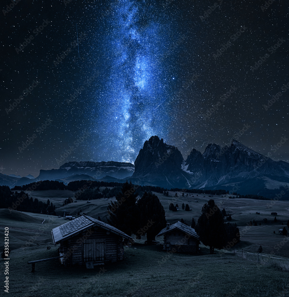 Milky way over wooden huts in Alpe di Siusi, Dolomites