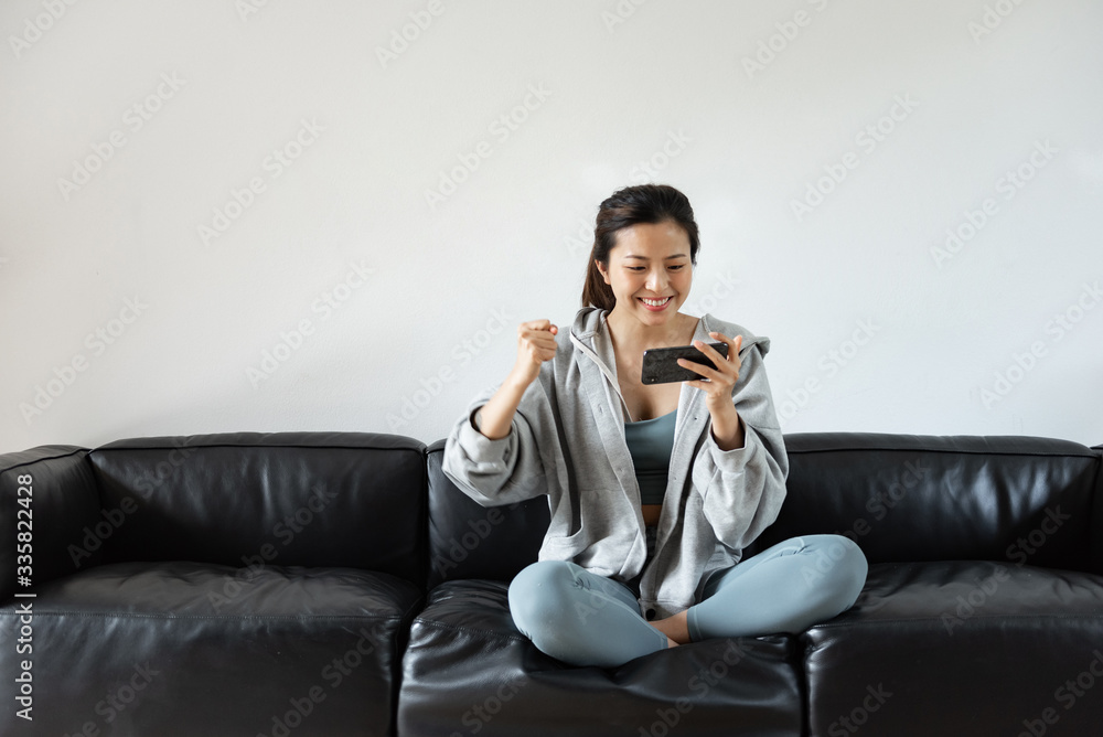 A young Asian woman using mobile phone in the living room A young Asian woman using mobile phone in the living room