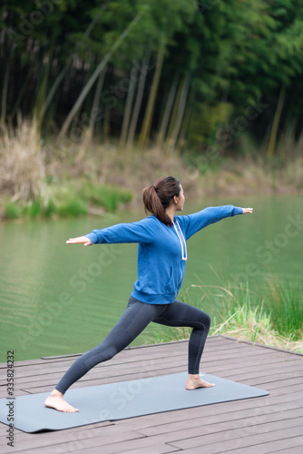 A young Asian woman doing yoga by the lake © 浩然 张