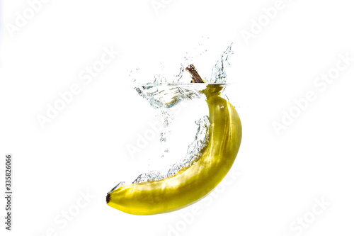 one banana falling into water on a white background with splashes