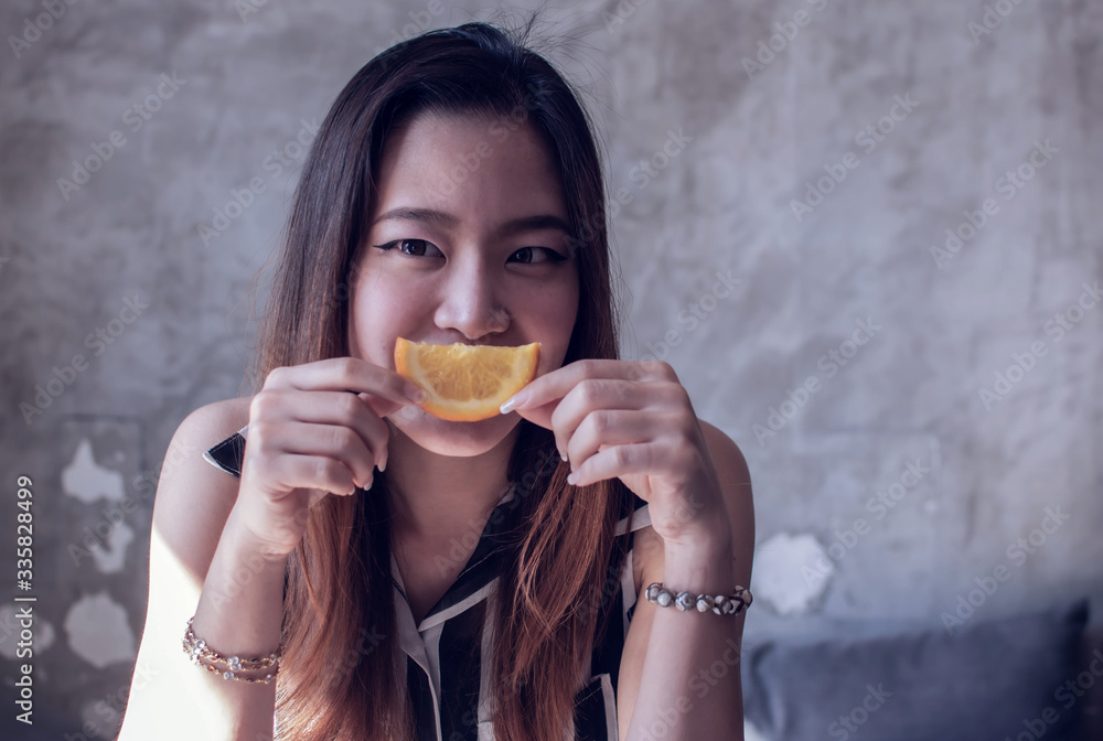 A woman is smiling and holding a piece of orange A woman is smiling and holding a piece of orange
