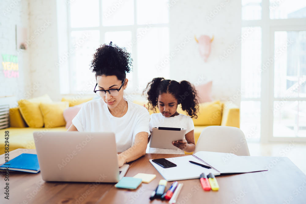 Black kid and parent interacting with devices - obrazy, fototapety, plakaty 