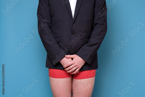Bilde på lerret Young caucasian man in suit and underpants on blue wall.