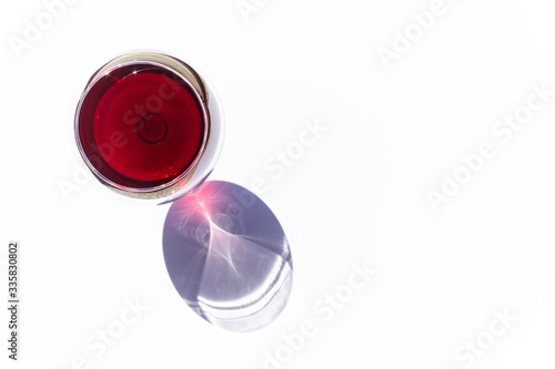 A glass of pink red wine on white background with sparkling shadows. Top view. Free copy space.  Concept of organic drinks.