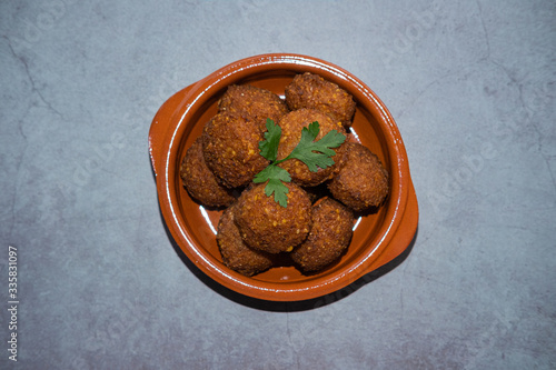 Falafel with parsley on top in a clay bowl on concrete background. Top view.view.