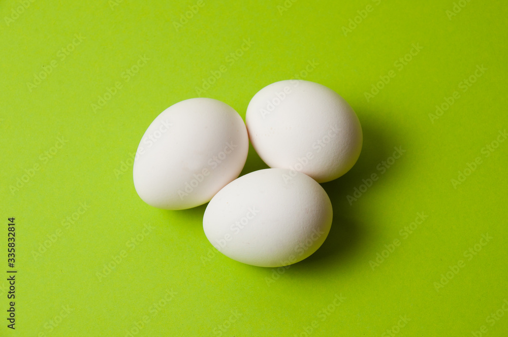 Several chicken eggs on bright green background, copy space Several chicken eggs on bright green background, copy space