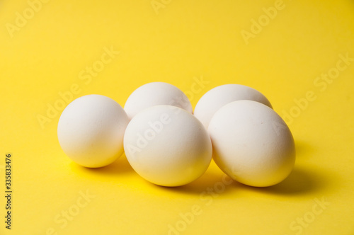 Several chicken eggs on a bright yellow background, copy space