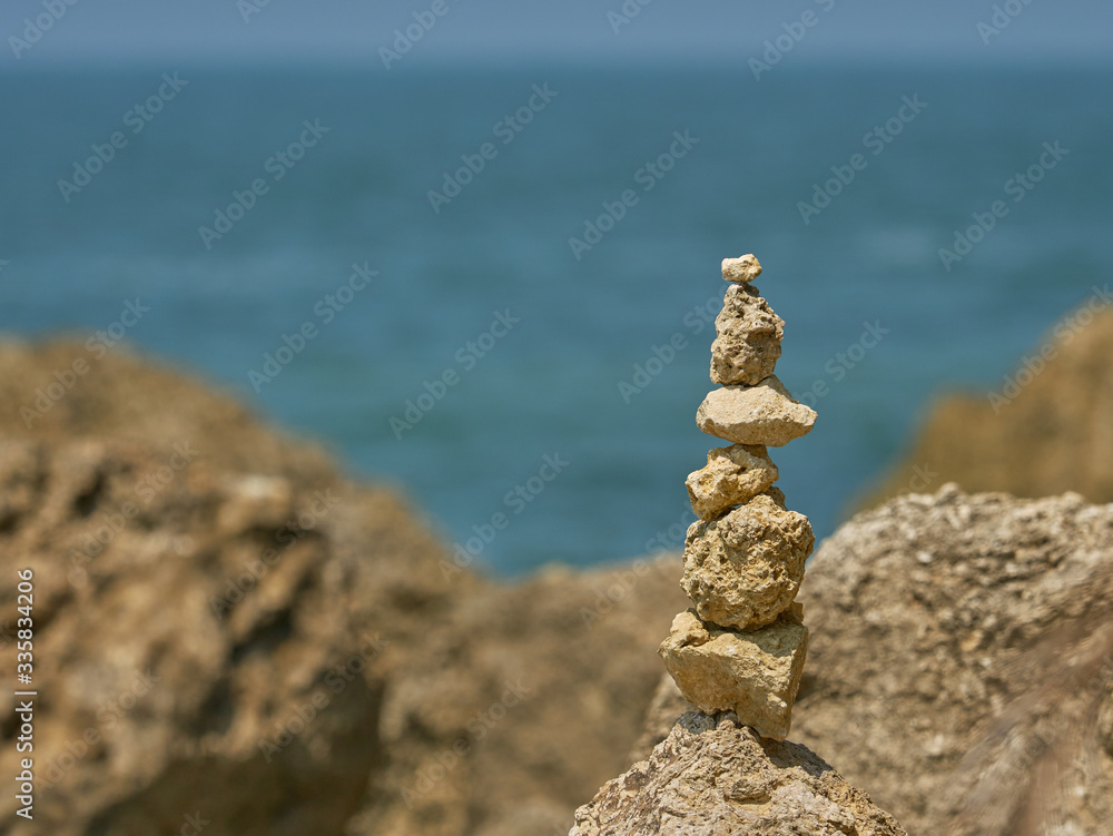 pile of stones from a beach stacked on top of each other with blurred ocean in the background