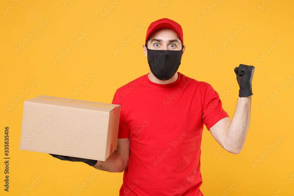 Delivery man employee in red cap blank t-shirt uniform face mask glove hold empty cardboard box isolated on yellow background studio Service quarantine pandemic coronavirus flu virus 2019-ncov concept