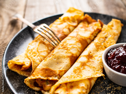 Sweet crepes with fruit jam on wooden table
