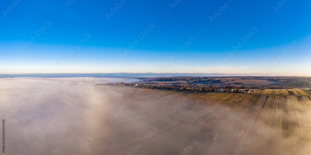 Beautiful panorama of winter village covered with dense fog from aerial view Beautiful panorama of winter village covered with dense fog from aerial view