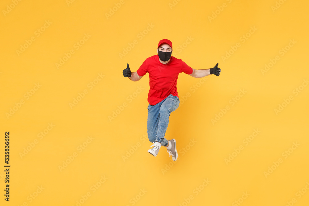 Fun jumping delivery man in red cap t-shirt uniform sterile face mask gloves isolated on yellow background studio Guy employee courier Service quarantine pandemic coronavirus virus 2019-ncov concept. Fun jumping delivery man in red cap t-shirt uniform sterile face mask gloves isolated on yellow background studio Guy employee courier Service quarantine pandemic coronavirus virus 2019-ncov concept.