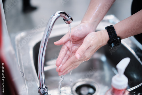 close up of female washing and rubbing hands with gel sanitizer soap cleaning in sink with tap water, staying safe and protect from bacteria, viruses and disease, public place being aware and safety