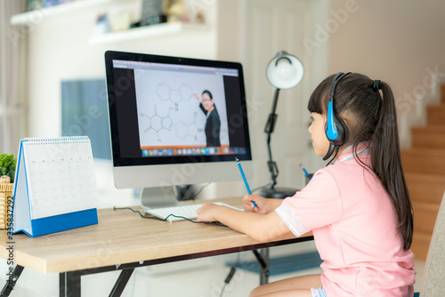 Asian girl student video conference e-learning with teacher on computer in living room at home. Homeschooling and distance learning ,online ,education and internet protect from COVID-19 viruses.