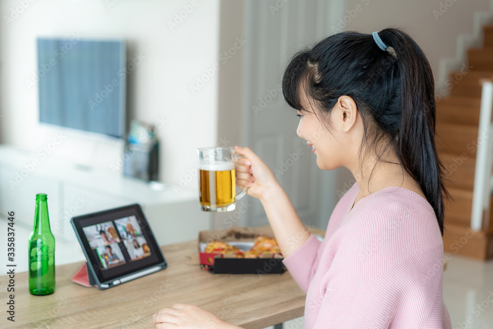 Asian woman virtual happy hour meeting party and drinking alcohol beer online together with her friend in video conference with digital tablet for a online meeting in video call for social distancing Asian woman virtual happy hour meeting party and drinking alcohol beer online together with her friend in video conference with digital tablet for a online meeting in video call for social distancing