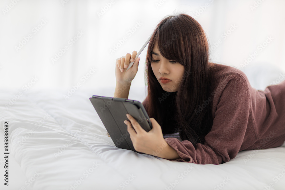Asian woman using tablet for working, educational, e-commerce, social media in her bed. corovavirus covid-19, stay at home, work form home concept. Asian woman using tablet for working, educational, e-commerce, social media in her bed. corovavirus covid-19, stay at home, work form home concept.