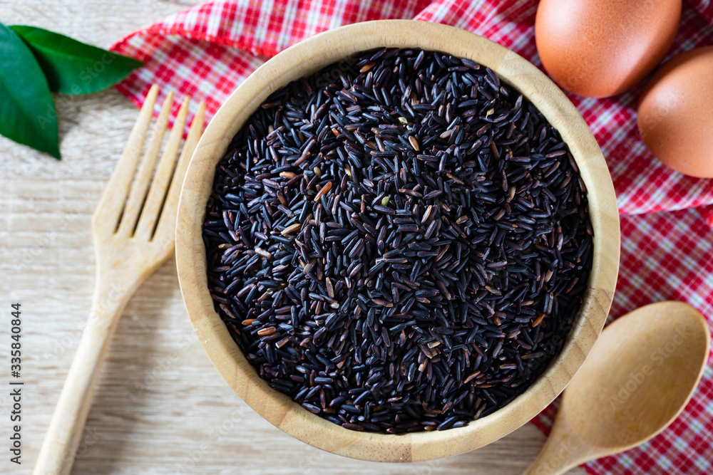 Thai black jasmine rice or Rice berry in wooden bowl and organic egg on paper tray with decorative background for healthy and organic food concept Thai black jasmine rice or Rice berry in wooden bowl and organic egg on paper tray with decorative background for healthy and organic food concept