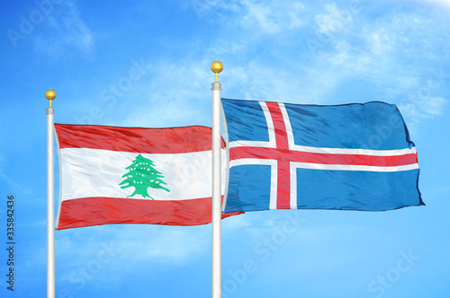 Lebanon and Iceland two flags on flagpoles and blue cloudy sky