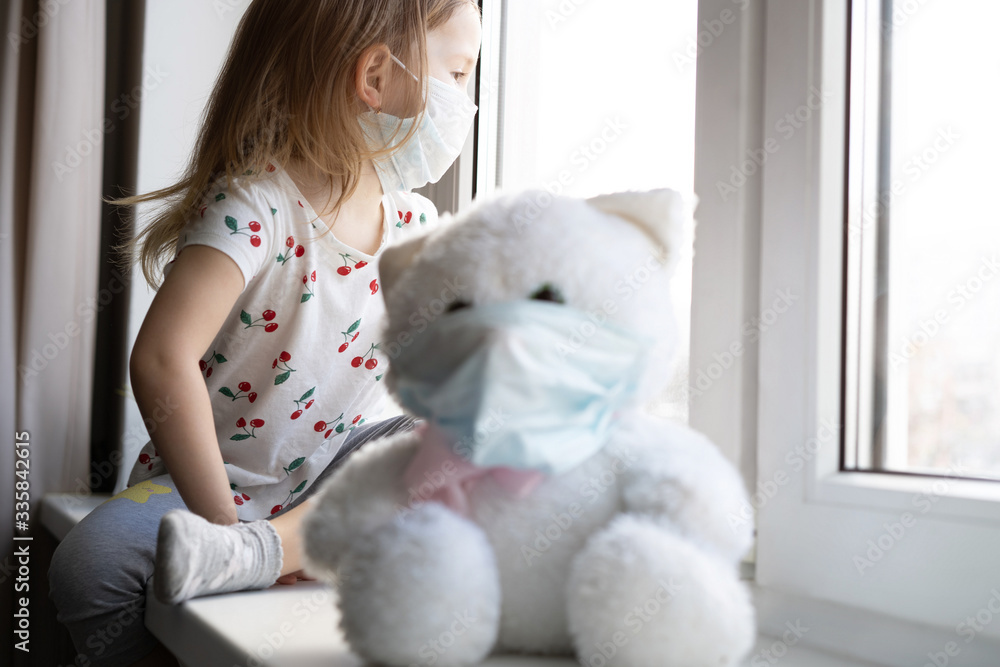 Sad child and his teddy bear both in protective medical masks. Children and illness COVID-2019 disease concept Sad child and his teddy bear both in protective medical masks. Children and illness COVID-2019 disease concept