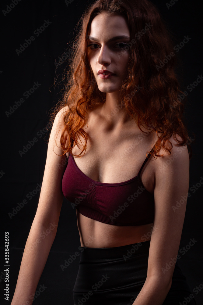 Naklejka premium Portrait of a young curly girl in a dark studio