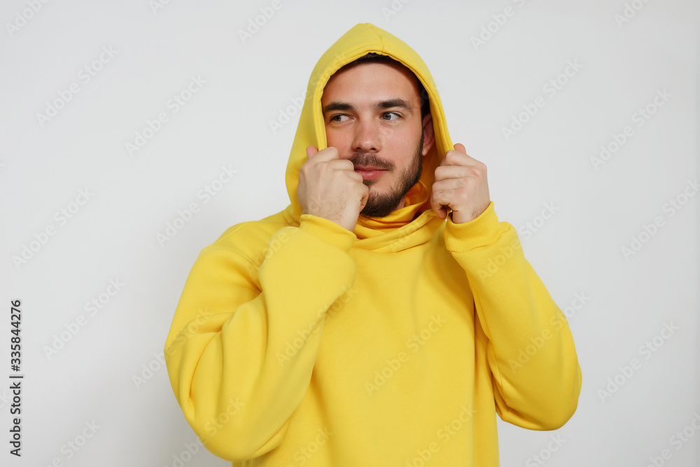 handsome bearded male model putting on yellow hoodie isolated on grey background handsome bearded male model putting on yellow hoodie isolated on grey background