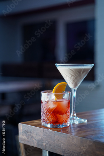 Classic cocktails on a wooden table in a loft bar, in cold neon light