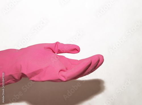 The pink glove dressed on a hand holds on a palm on a white background
