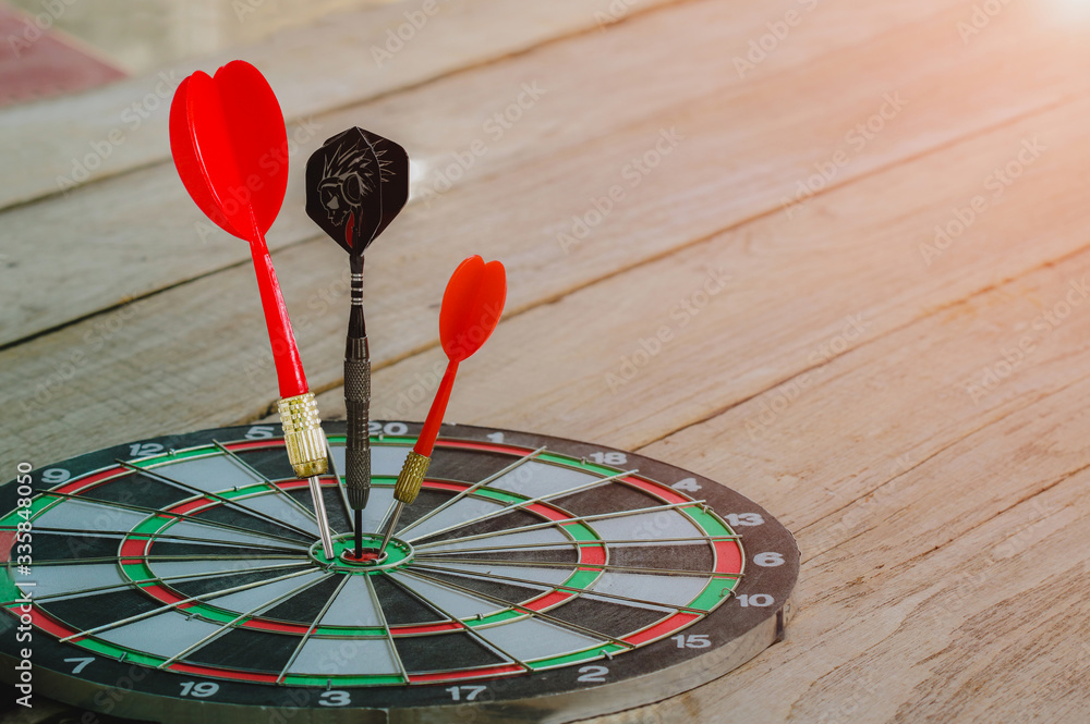 Fototapeta premium red and Black Dart arrow hitting on center dart board, Success hitting target aim goal achievement concept background – three dart in bull’s eye close up,