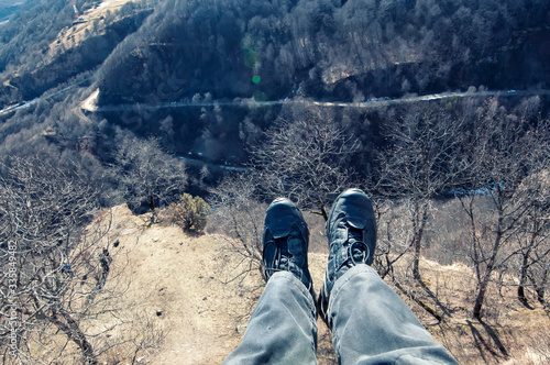 First person perspective shot from a hiker sitting at the edge of a cliff.