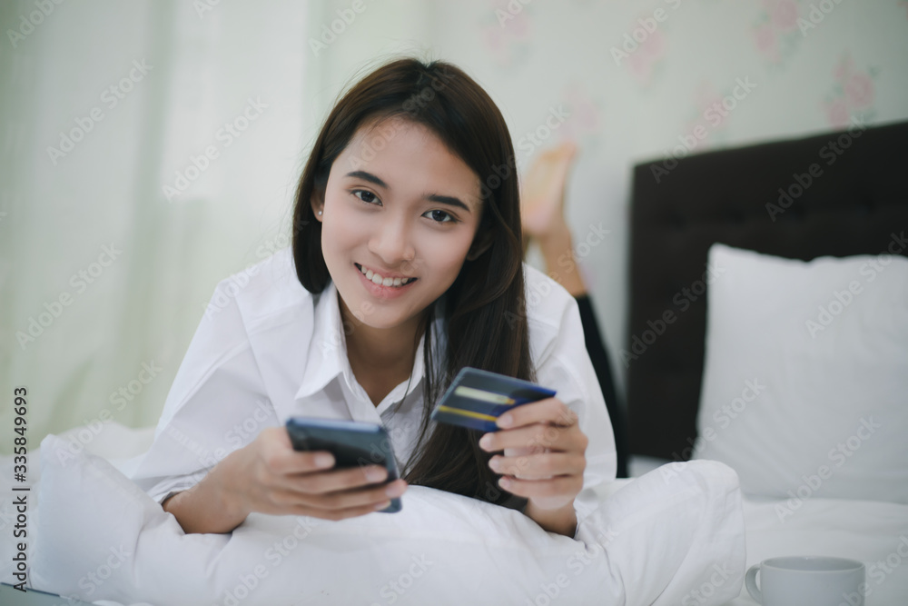 Asian women shopping online and paying with credit card on mobile phone. and Happy women at home surfing the net in bed Asian women shopping online and paying with credit card on mobile phone. and Happy women at home surfing the net in bed