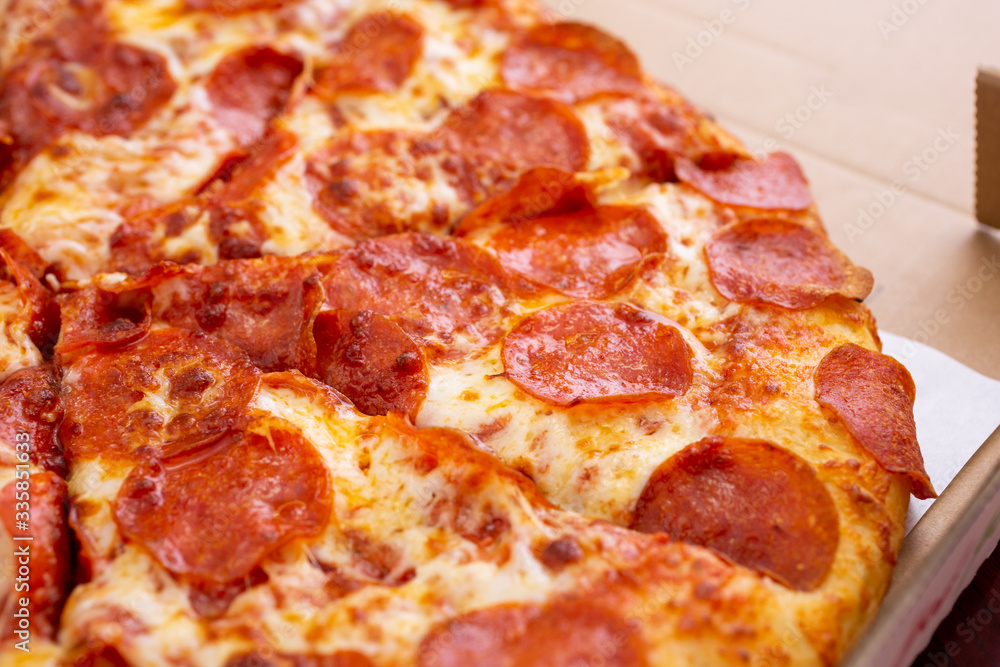 A closeup view of a standard pepperoni pizza pie, inside a pizza box, in a restaurant or kitchen setting. A closeup view of a standard pepperoni pizza pie, inside a pizza box, in a restaurant or kitchen setting.